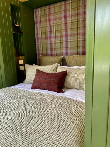 a bed with two red pillows on top of it at The Box Car with Outdoor Private Bath in Closeburn