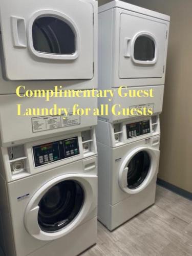 two washing machines in a laundry room with a poster at Ocean Sands Beach Boutique Inn-1 Acre Private Beach-St Augustine Historic-2 Miles-Shuttle with Downtown Tour-HEATED Salt Water Pool until 420AM-Popcorn-Cookies-New 4k USD Black Beds- 69 Item Breakfast-Eggs-Bacon-Starbucks- Free Laundry- #904-799-SAND in Saint Augustine