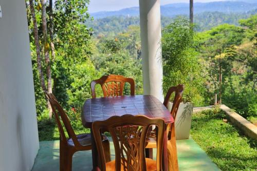 a wooden table and chairs on a porch with a view at Warmy Treat Hotel in Kandy