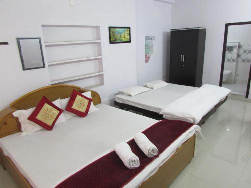 two beds in a room with white walls at Ashish Guest House, Goverdhan Vilas in Udaipur