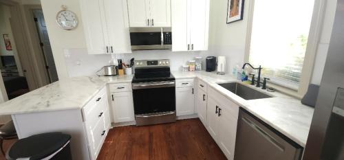 a kitchen with white cabinets and a black stove top oven at La Belle Cottage II 2queenbeds 10min to French Qtr in New Orleans