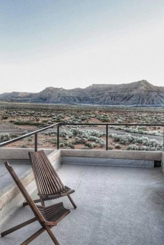 a wooden chair sitting on a balcony looking at the desert at Canyon Mesa Haven, Luxury Stay near Lake Powell in Big Water