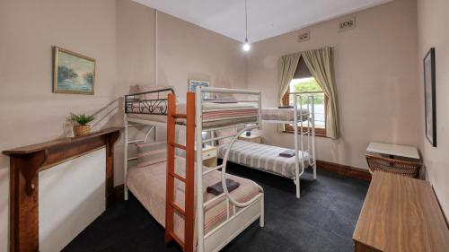 a room with two bunk beds and a desk at Union Hotel Tumbarumba in Tumbarumba