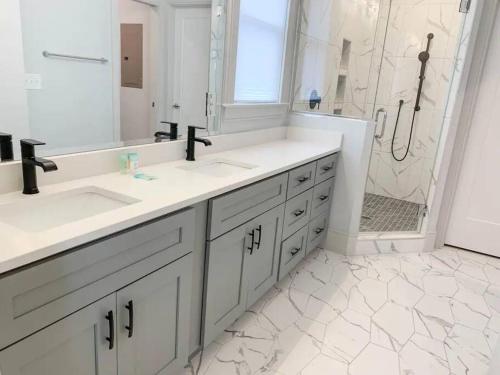 a white bathroom with two sinks and a shower at City View- near Downtown, Capital, NC State in Raleigh
