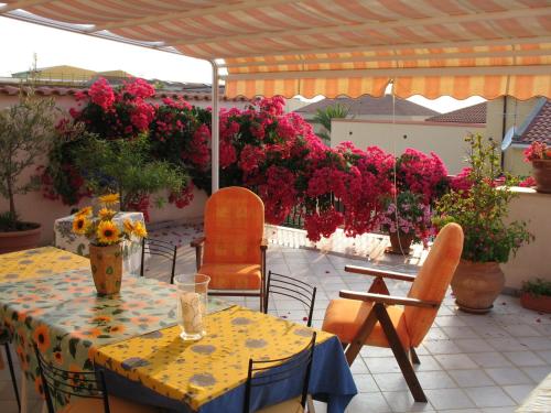- une terrasse avec une table, des chaises et des fleurs dans l'établissement B&B Le Terrazze, à Capo dʼOrlando