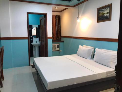 a bedroom with a white bed with a blue wall at SG Hotel in El Nido