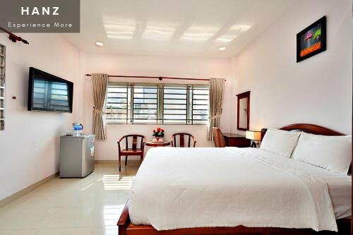 Un dormitorio con una gran cama blanca y una mesa en HANZ Hoang Hoang Hotel Ben Thanh en Ho Chi Minh