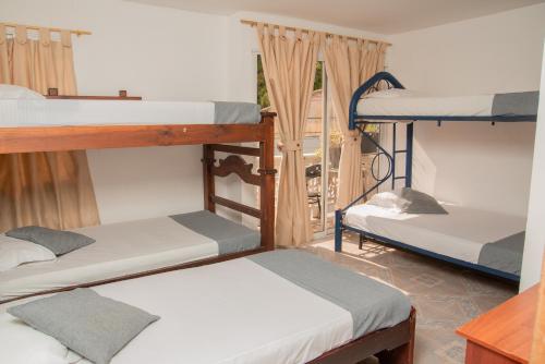 a room with three bunk beds and a balcony at Marias House - Magnifique Hotels in Santa Marta