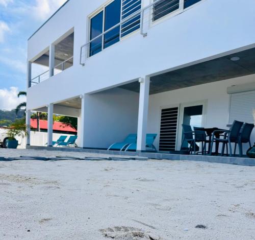 a white house with blue chairs and a patio at Pension Irivai, appartement UO UO 3 chambres vue mer in Uturoa