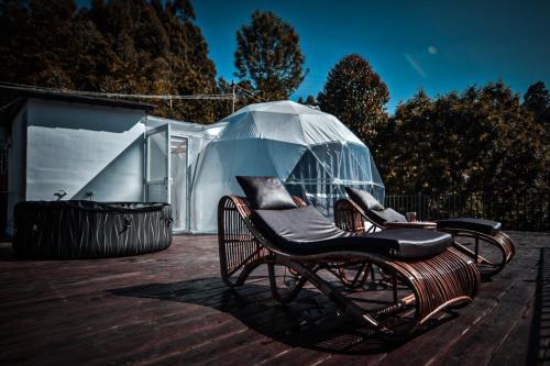 a chair on a deck with a clear umbrella at Divercity Luxury Glamp in Kodaikānāl