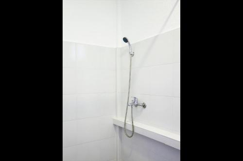 La salle de bains est pourvue d'une douche et de carrelage blanc. dans l'établissement La Pang Resort 라팡리조트, à Panglao