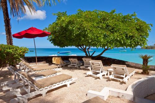 a group of lounge chairs and an umbrella on the beach at Le Beachclub in Pereybere