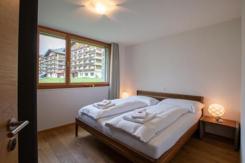 een slaapkamer met een bed met witte lakens en een raam bij Alpenresort B22 in Riederalp
