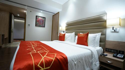 a hotel room with a large bed with orange pillows at Ramada by Wyndham Aligarh GT Road in Alīgarh
