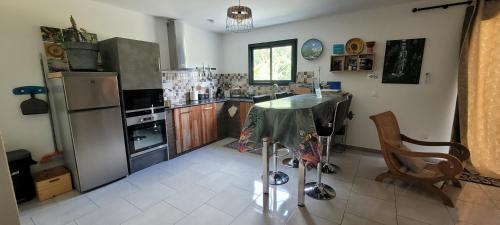 a kitchen with a table and a refrigerator at Le Refuge d'Heva in Salazie