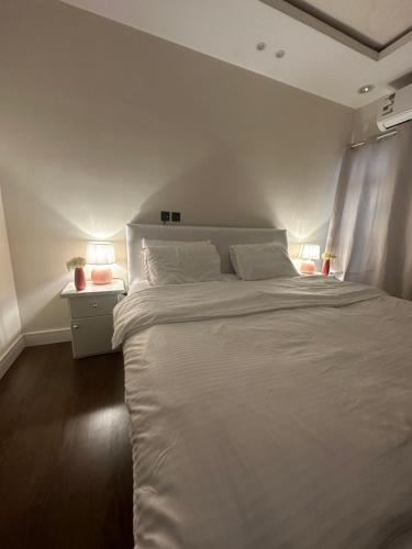simple house في الرياض: غرفة نوم بسرير ابيض كبير ومصباحين