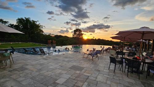 uma piscina com pessoas sentadas na água ao pôr do sol em Resort QSB - Conforto e Lazer no Centro - Proprietário em Pirenópolis