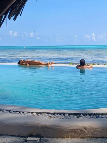 two people swimming in a pool in the ocean at Driftwood Beach Lodge in Jambiani