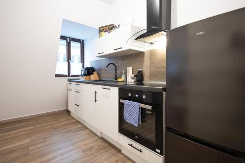a kitchen with a black oven and white cabinets at Apartments am Neuen Theater - Altstadt - Zentral - Küche - Wifi - Powered by Ko-Living in Halle an der Saale