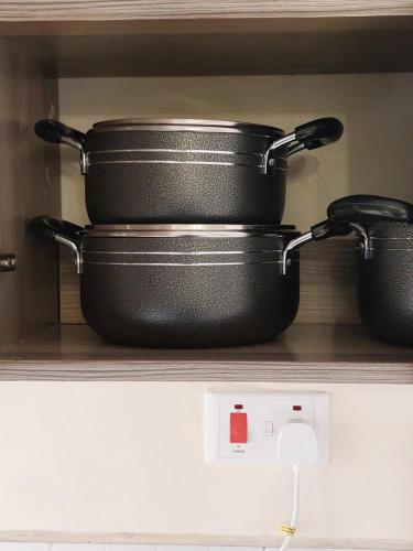 two pans sitting on a shelf in a kitchen at Rawin Homes in Nyeri