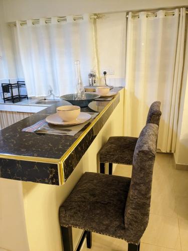 a kitchen with a counter with a sink and chairs at Rawin Homes in Nyeri