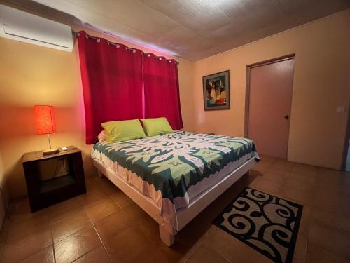 - une chambre avec un lit et un rideau rouge dans l'établissement La maison près du Phare, à Mahina
