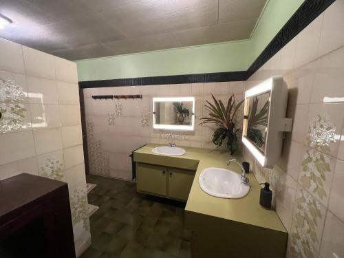 a bathroom with two sinks and a mirror at La maison près du Phare in Mahina