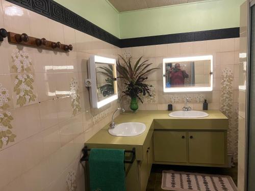 a bathroom with two sinks and two mirrors at La maison près du Phare in Mahina