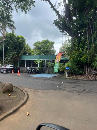 a parking lot with a green building next to a street at La maison près du Phare in Mahina