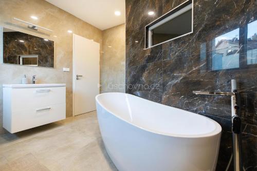 a bathroom with a white tub and a sink at Airport Luxury Apartment Prague in Prague