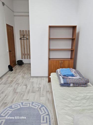 1 dormitorio con 1 cama y suelo de madera en Kamkor, en Atyraū