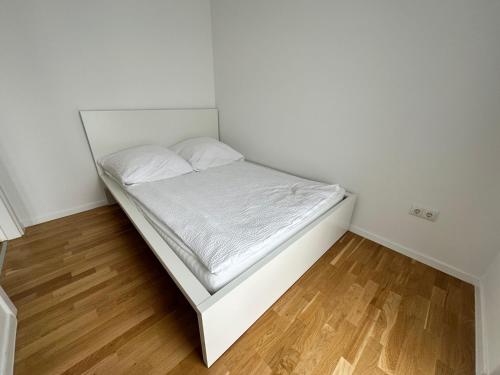 um pequeno quarto com uma cama com lençóis brancos em Gemütliche Wohnung mit Terrasse em Blumberg