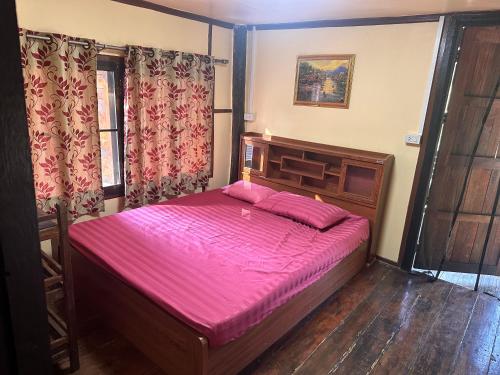 a bedroom with a large bed with a pink sheets at NADOHN2 Nai Fan Homstay in Rayong