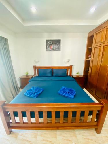 a bedroom with a large wooden bed with blue sheets at BT hotel Kata Beach in Kata Beach