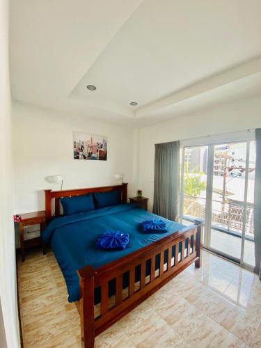 een slaapkamer met een bed met blauwe lakens en een balkon bij BT hotel Kata Beach in Kata Beach