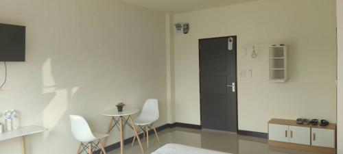 een kamer met een zwarte deur en een tafel en stoelen bij TPR51 Room Service in Ban Hua Khao Sammuk