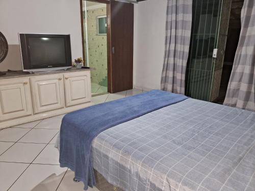 een slaapkamer met een tv en een bed met een blauwe deken bij Casa da Praia em Costazul in Rio das Ostras
