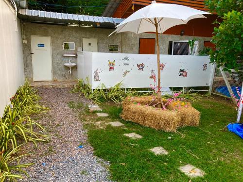 a garden with an umbrella and hay bales at เดอะมินิมอล นอร์ดิกเฮ้าส์The Minimal Nordic House By The Mountain Ozoneบ้านโอโซนขุนเขาแก่งกระจาน in Kaeng Krachan