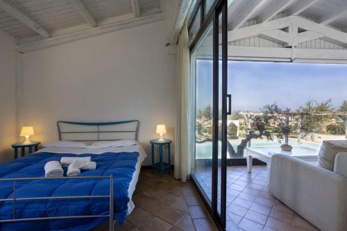 een slaapkamer met een blauw bed en een groot raam bij Stunning apartment in the nature with dreamy view in Parrinello 