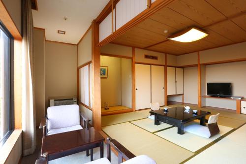 salon ze stołem, krzesłami i telewizorem w obiekcie Motoyu Kosenkaku w mieście Kobe