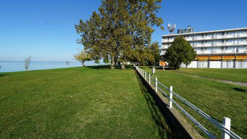 einen Zaun auf einem Feld neben einem Gebäude in der Unterkunft Plazs Hotel Siófok in Siófok