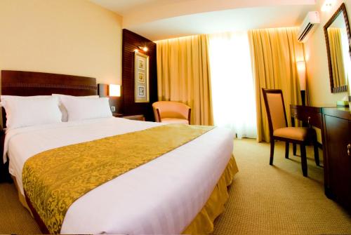 una camera d'albergo con un grande letto e una scrivania di Celyn Hotel City Mall a Kota Kinabalu