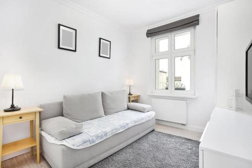 a white living room with a couch and a window at Pegaz 4 in Sopot