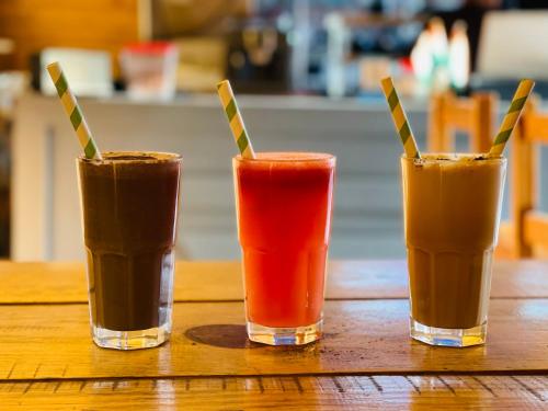 three different colored drinks sitting on a wooden table at BLACKVILLA in Mukteswar