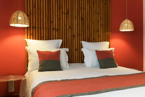 a bedroom with a bed with red walls and white pillows at Nosy Manga - Hotel Ivato Airport in Antananarivo
