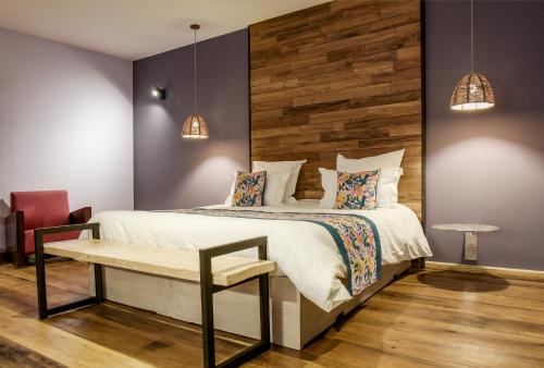 a bedroom with a large bed and a bench at Nosy Manga - Hotel Ivato Airport in Antananarivo