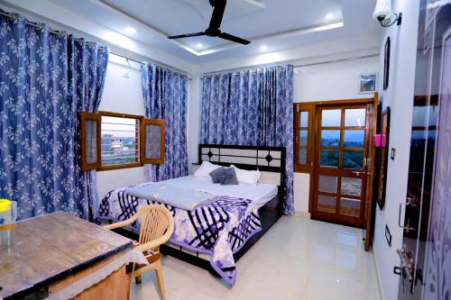 Schlafzimmer mit einem Bett mit blauen Vorhängen und einem Fenster in der Unterkunft Bhagora CJMA Home Stay/Villa in Udaipur