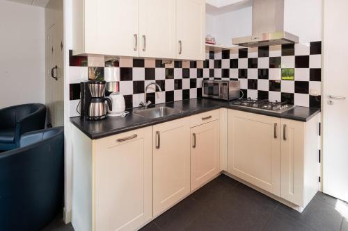 a kitchen with white cabinets and a black and white checkered wall at Hoeve Montigny B&B in Giethoorn