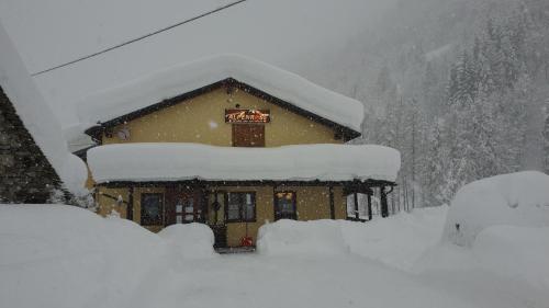 un bâtiment recouvert de neige sur le toit dans l'établissement Rifugio Alpenrose, à Carcoforo