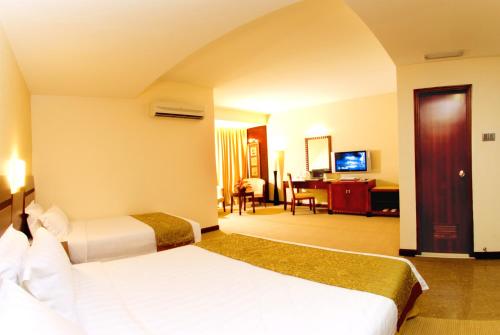 a hotel room with two beds and a living room at Celyn Hotel City Mall in Kota Kinabalu